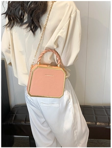 Detail of pink box bag with gold metal trim and twisted handle worn by model