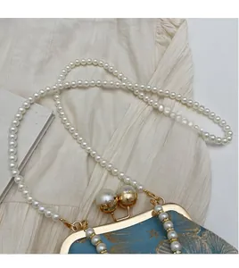 Close-up of blue jacquard handbag with pearl clasp and luxury faux pearl shoulder strap