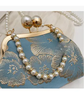 Detail of blue satin evening bag with gold floral embroidery and large pearl clasp