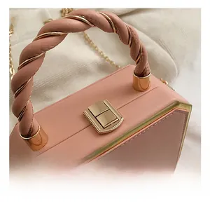Macro view of light pink box bag with twisted leather gold handle and metallic lock