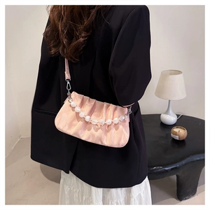 Roze geplooide crossbodytas met acryl parelhandvat gedragen door model in moderne kamer