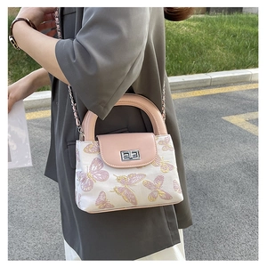Close-up of white fabric bucket bag with pink butterfly embroidery and silver chain