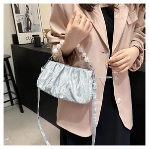 Detail van zilveren geplooide cloud-tas met parelhandvat en metallic afwerking