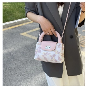 Outdoor shot of a quilted mini bucket bag with butterfly print and pink leather details