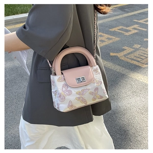 Detail of pink and white quilted bucket bag with butterfly pattern and metal chain strap