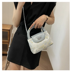 Detail of light blue bucket bag featuring elegant butterfly embroidery and metallic clasp