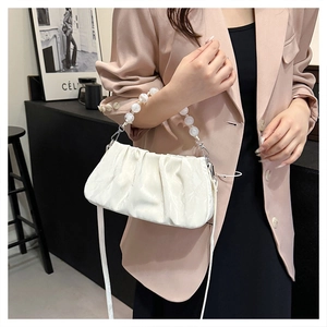 Detail van witte geplooide cloud bag met acryl parelhandvat en lederen schouderriem