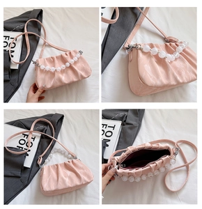Detail van roze geplooide handtas met parelketting en rode binnenvoering
