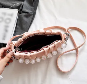 Roze geplooide crossbodytas met grote parelhandgreep en donkerrode binnenvoering