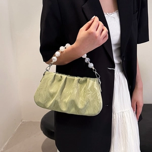 Lichtgroene geplooide crossbodytas met luxe parelhandvat en glanzende afwerking op model