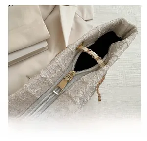 Dettaglio della cerniera dorata e trama in tweed della borsa a tracolla con catena
