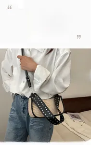 Detail of straw woven crossbody bag with black leather trim and studded shoulder strap
