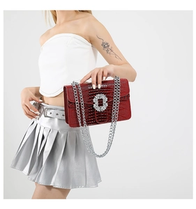 Close-up of red crocodile embossed shoulder bag featuring a luxury rhinestone buckle