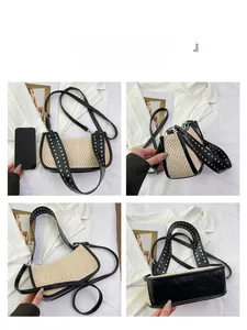 Detail view of woven straw shoulder bag with silver rivet studs and black leather base