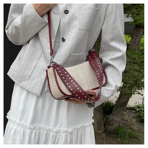 Detail of woven straw shoulder bag with red leather trim and silver rivets decoration
