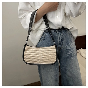 Detail of woven crescent bag with rivet leather strap and beige straw texture