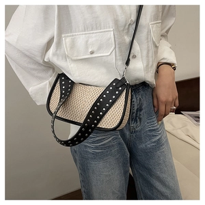 Detail of straw crossbody bag with studded wide leather strap and rivet decorations