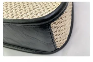 Close-up of straw woven texture with black leather trim and stitching on shoulder bag