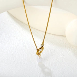 Collier chaîne serpent dorée avec perle blanche sur fond minimaliste à texture blanche