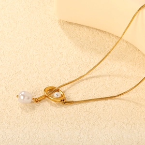 Collier chaîne serpent dorée avec pendentif perle élégant sur fond beige texturé