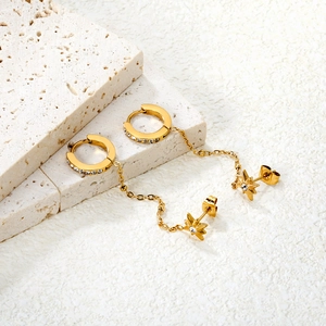 Gold eight-pointed star earrings with chains and sparkling crystals on travertine stone