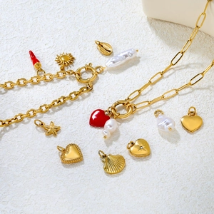 Golden multi-charm necklace with red heart, chili, starfish and pearls on white texture