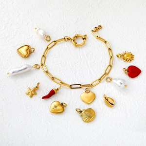 Gold chain bracelet featuring assorted heart, starfish, and red chili pendants on white background