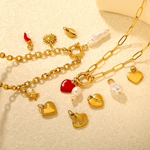 Gold stainless steel chain with heart, starfish and pearl charms on beige texture