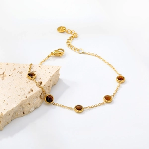 Gold stainless steel bracelet with five round tiger eye stones on light stone background