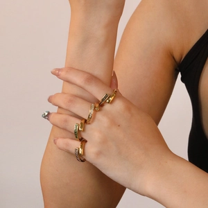 Detail of stacked vintage gold rings with emerald and zircon stones on a model