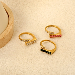 Macro detail of three gold rings with emerald-cut crystals and side-set sparkling diamonds