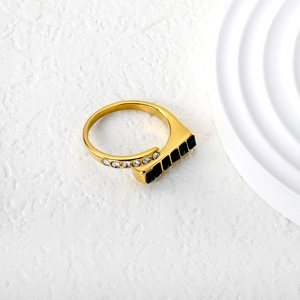 Detail of gold geometric ring featuring emerald-cut green stones and micro-pave zircons