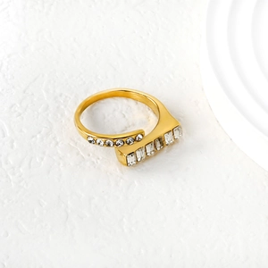 Macro view of gold adjustable ring with emerald-cut crystals on textured background