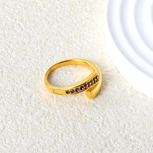 Detail of gold open ring with purple crystals on a textured white background