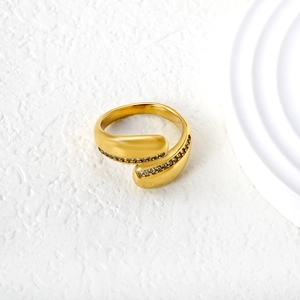 Detailed close-up of golden bypass ring featuring pave-set crystals and emerald details