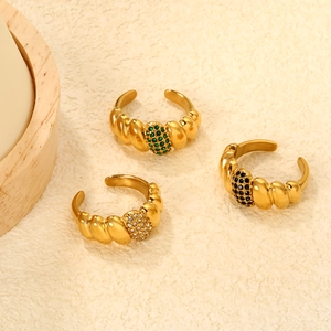 Detailed view of three gold vintage twisted rings with emerald and crystal inlays