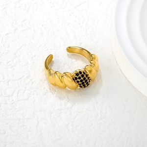 Detail of vintage emerald-style gold ring with black pavé crystals on textured background