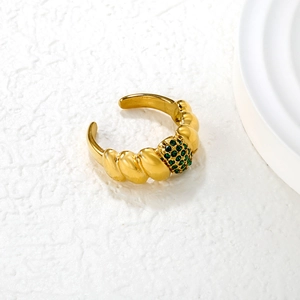 Close-up of golden croissant ring with green pave stones and vintage textured band