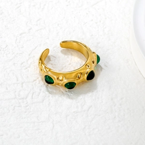 Detailed macro of gold vintage ring with emerald green stones and hammered texture