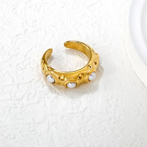 Irregular textured gold open ring with emerald-like cat eye and pearls on white surface