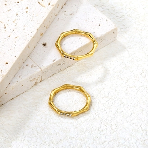 Macro detail of gold bamboo texture rings featuring purple and clear gemstone accents