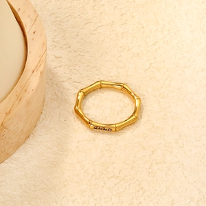 Close-up of bamboo design gold ring with purple zircon stones on textured fabric