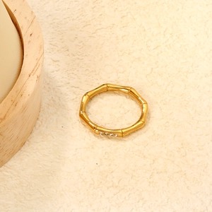 Macro shot of bamboo-style gold ring with four inset diamonds on stone base