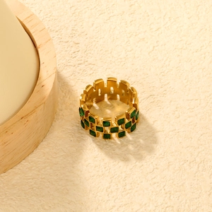 Macro detail of gold-plated bamboo texture ring with emerald green square gemstones