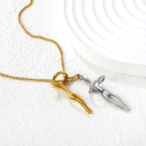 Minimalist abstract human pendant necklace in gold and silver finish on white sand