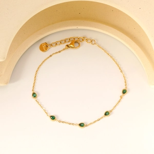 Détail du bracelet en acier inoxydable doré avec cinq pierres vert émeraude taille poire