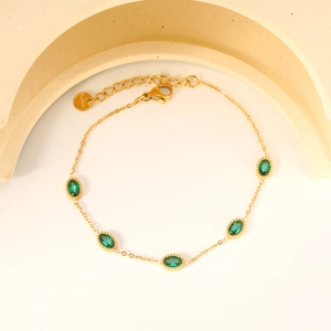 Détail d'un bracelet ajustable en acier doré orné de cinq pierres ovales vert émeraude
