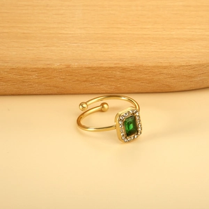 Vue détaillée d'une bague dorée réglable avec pierre vert émeraude et halo brillant