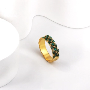 Vue détaillée d'une bague tennis dorée avec pierres précieuses vert émeraude carrées