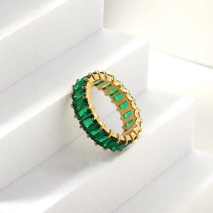 Vue macro d'une bague d'éternité dorée avec pierres vertes taille émeraude
